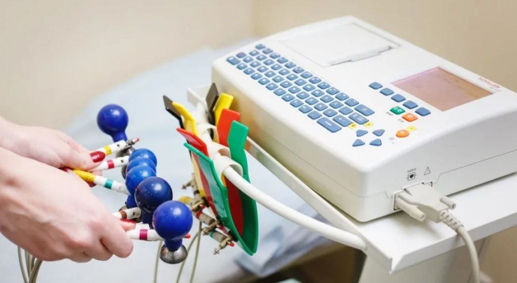 A medical technician prepares to use an ECG machine with electrode cables.